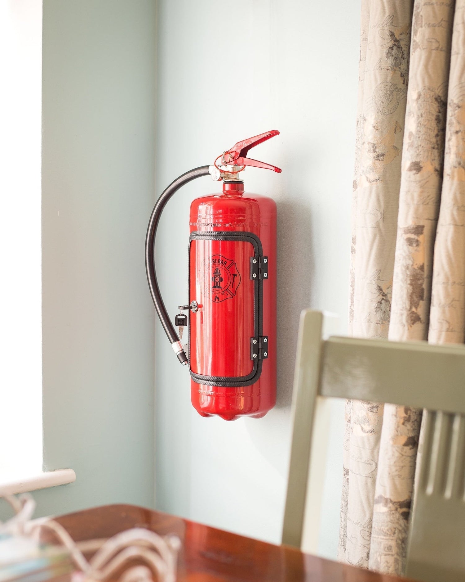 Closed wall-mounted fire extinguisher mini bar cabinet in red with hose and locking door