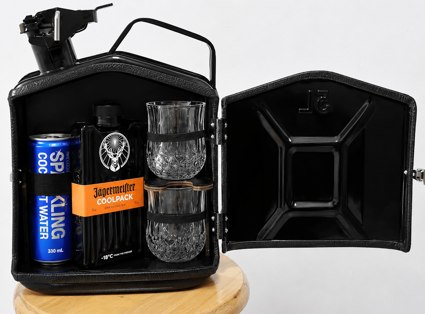 Black jerry can mini bar open with Jagermeister bottle and stacked glasses on a wooden stool